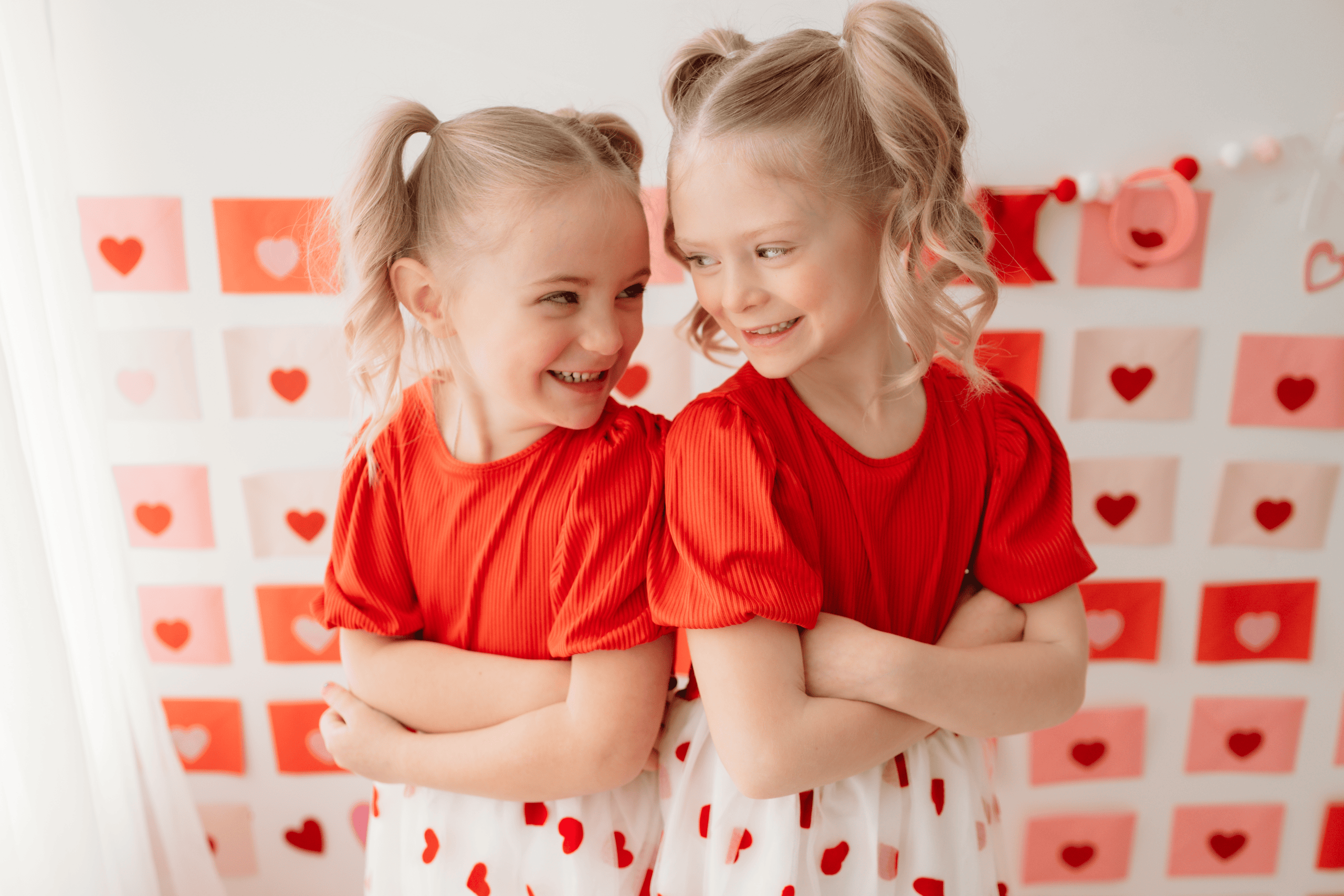 Valentine Mini photo session featuring two smiling young girls in red dresses for Valentine's Day.